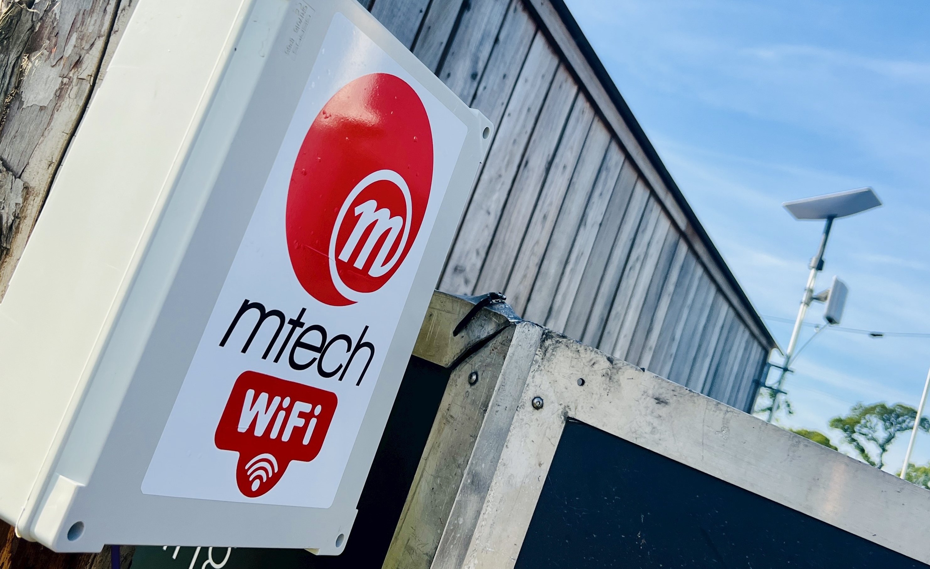Branded M-Tech weather-proof Wi-Fi enclosure on site at Chiddfest, with Starlink terminal visible in the background